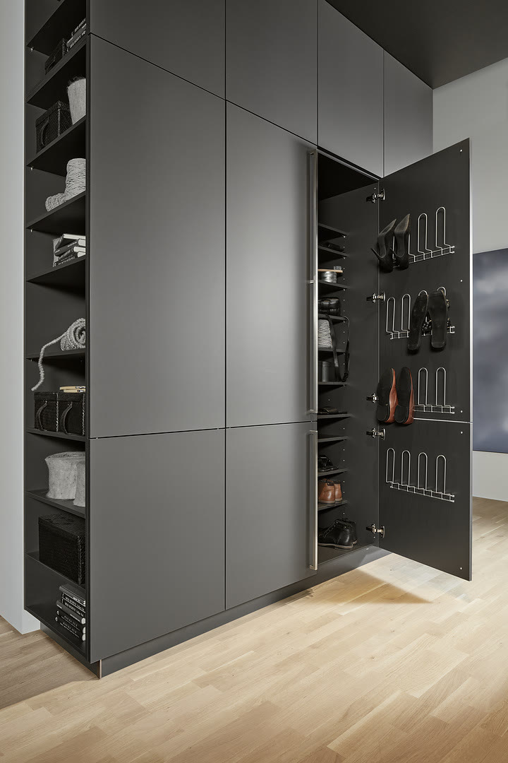 Gray handleless cabinet with pull-out wire racks holding cookware and a separate open shelving section