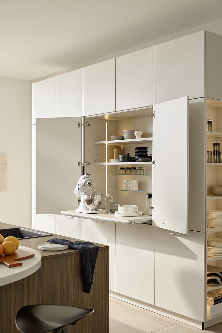White handleless kitchen with a curved wood-grain island, open shelving, and a stone countertop