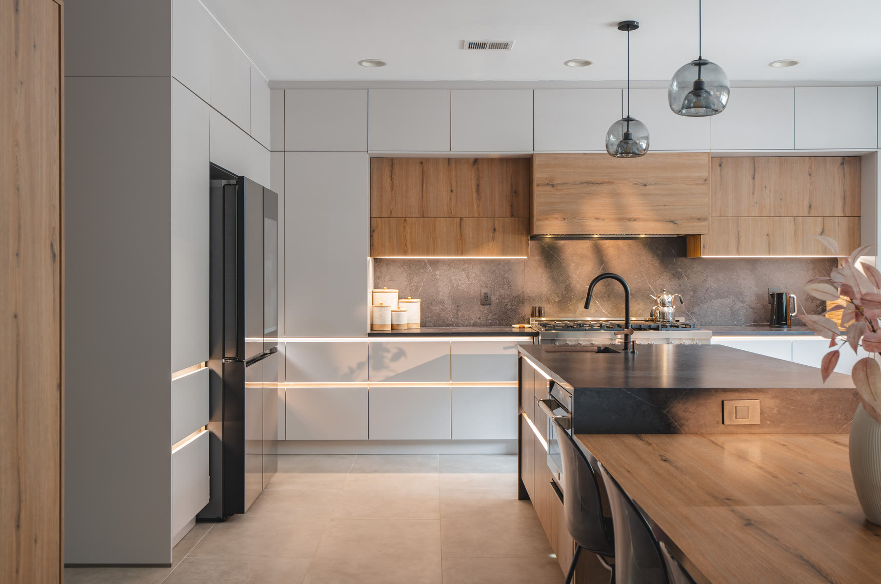 Finished kitchen with white handleless upper cabinets, warm wood lower cabinets, and a waterfall-edge wood island