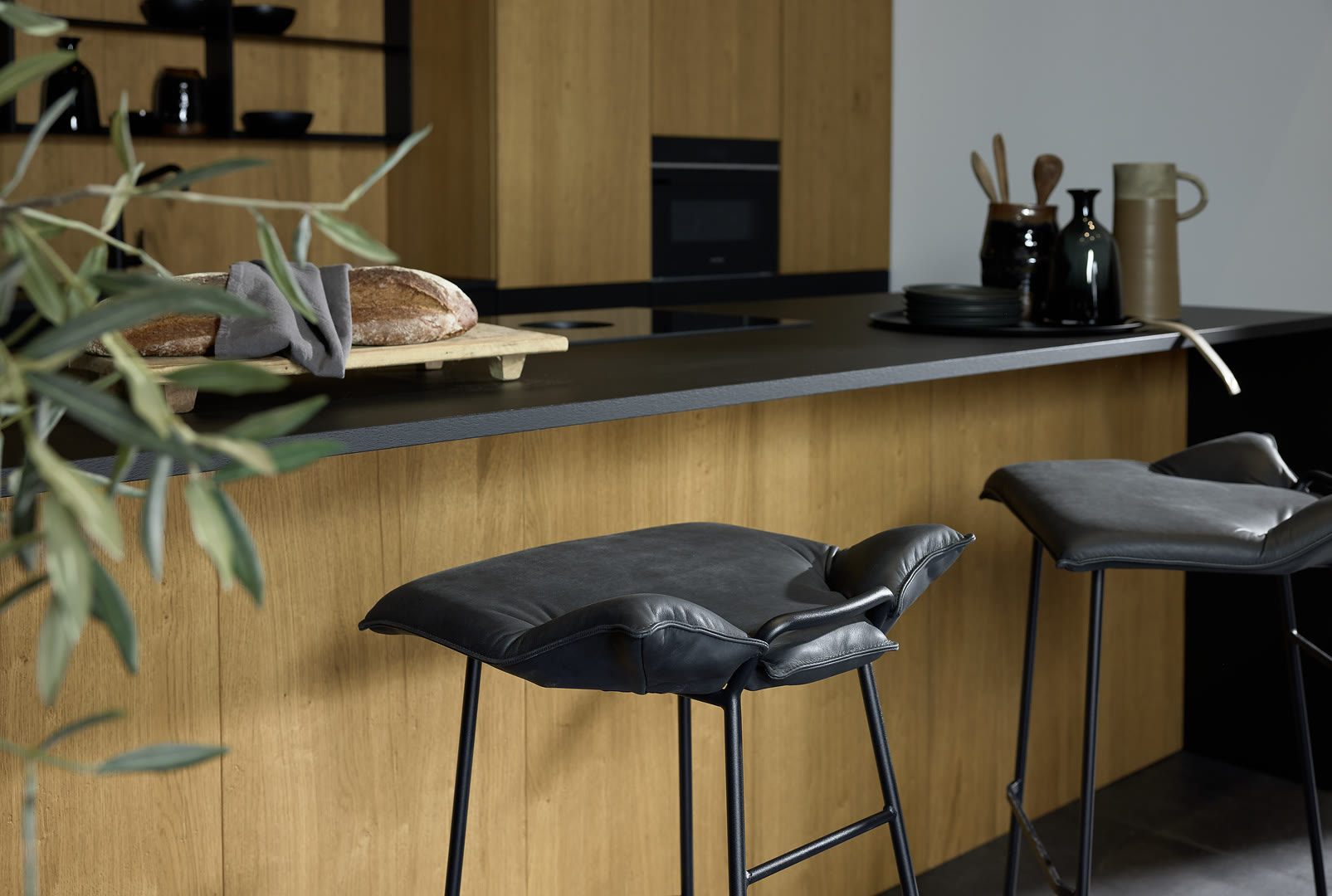 Kitchen with natural wood cabinet fronts, a dark countertop island, and built-in wall ovens