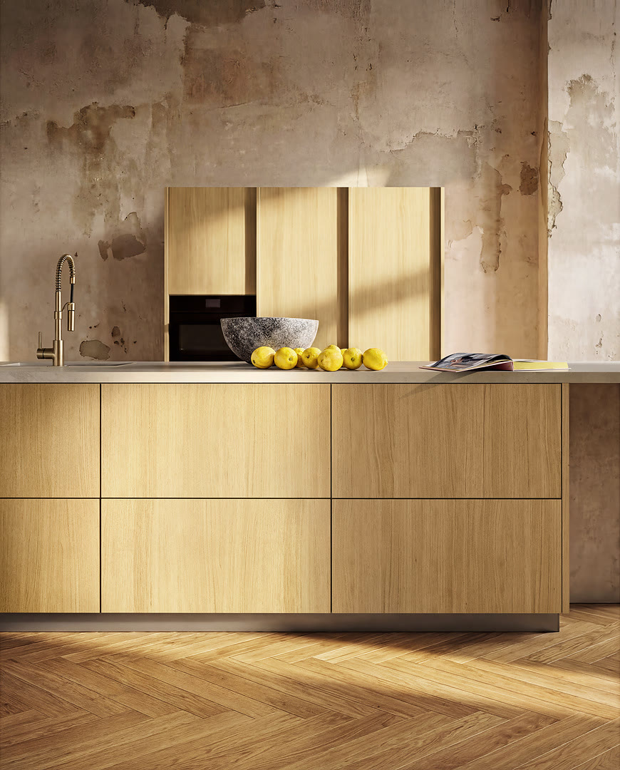 Pale oak handleless island with two rows of full-width drawers under a stone worktop with an integrated sink and brass tap.