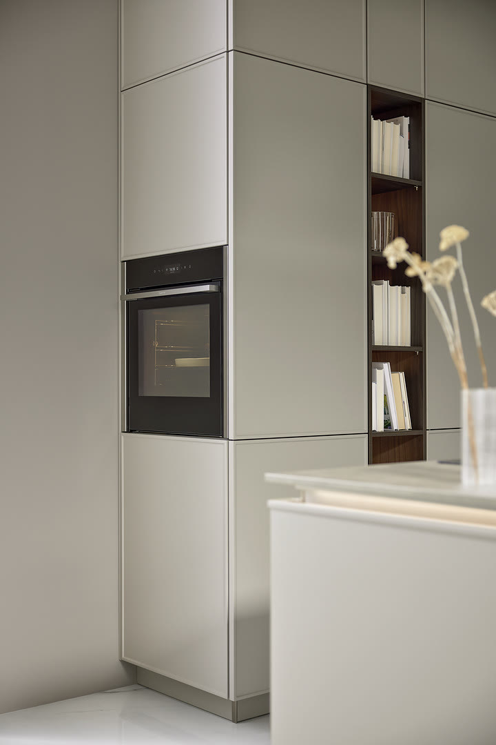 Light grey handleless tall cabinets with a built-in oven, open shelving, and a white island
