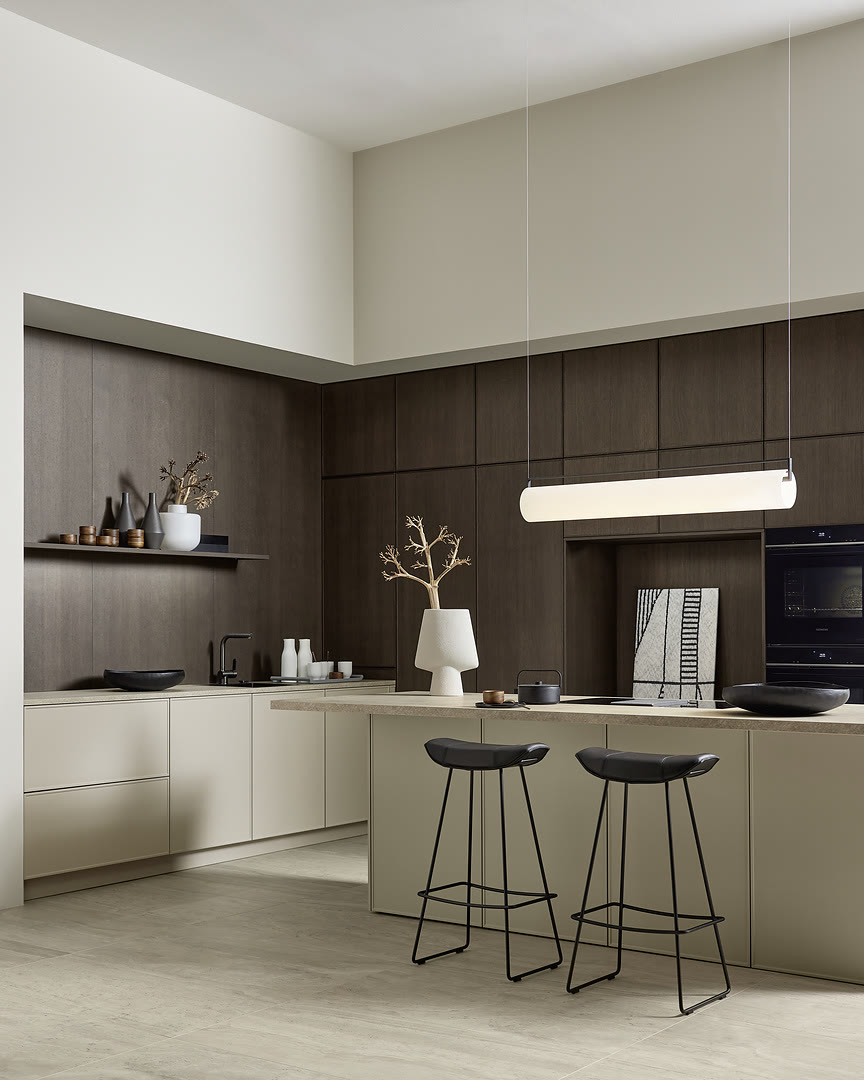 A kitchen with cream and dark wood-grain cabinets and an island with two bar stools.