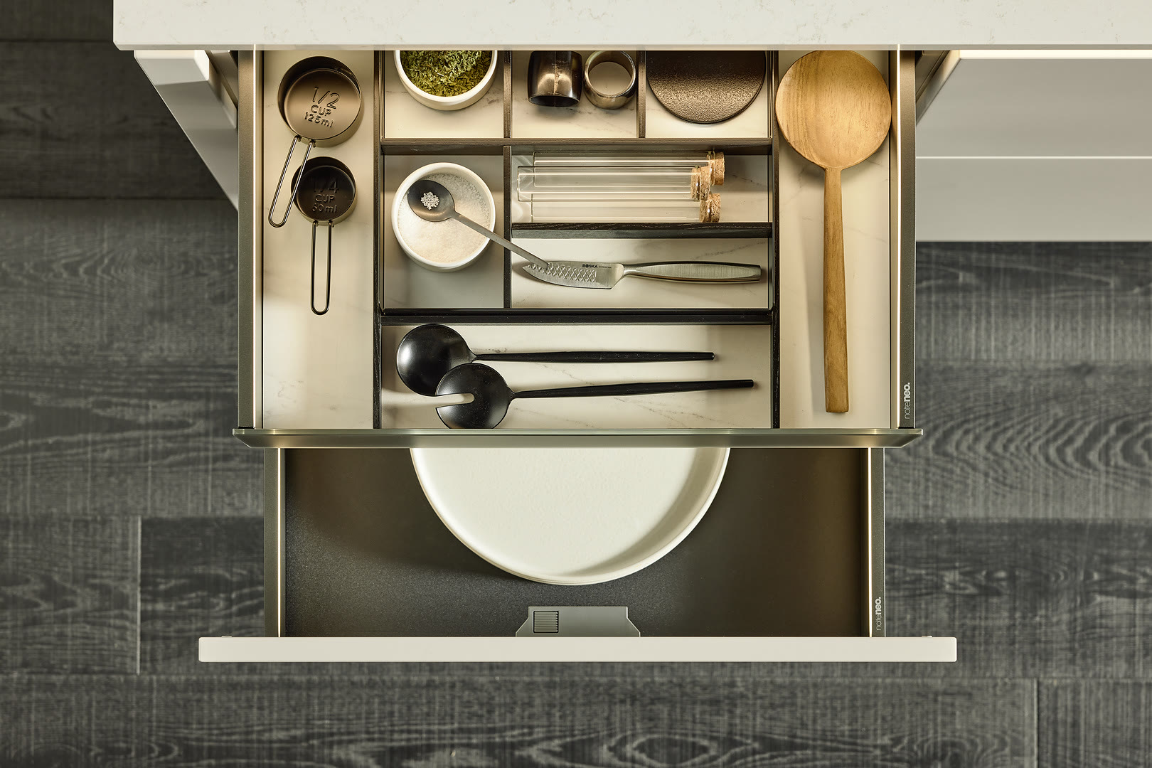 An open kitchen drawer with a fabric-lined organizer holding cookware and utensils.