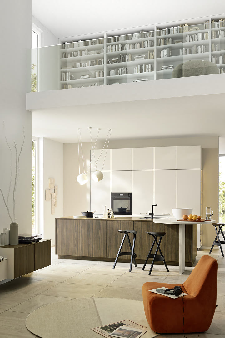A kitchen with white upper cabinets, warm wood lower cabinets, and a waterfall island.