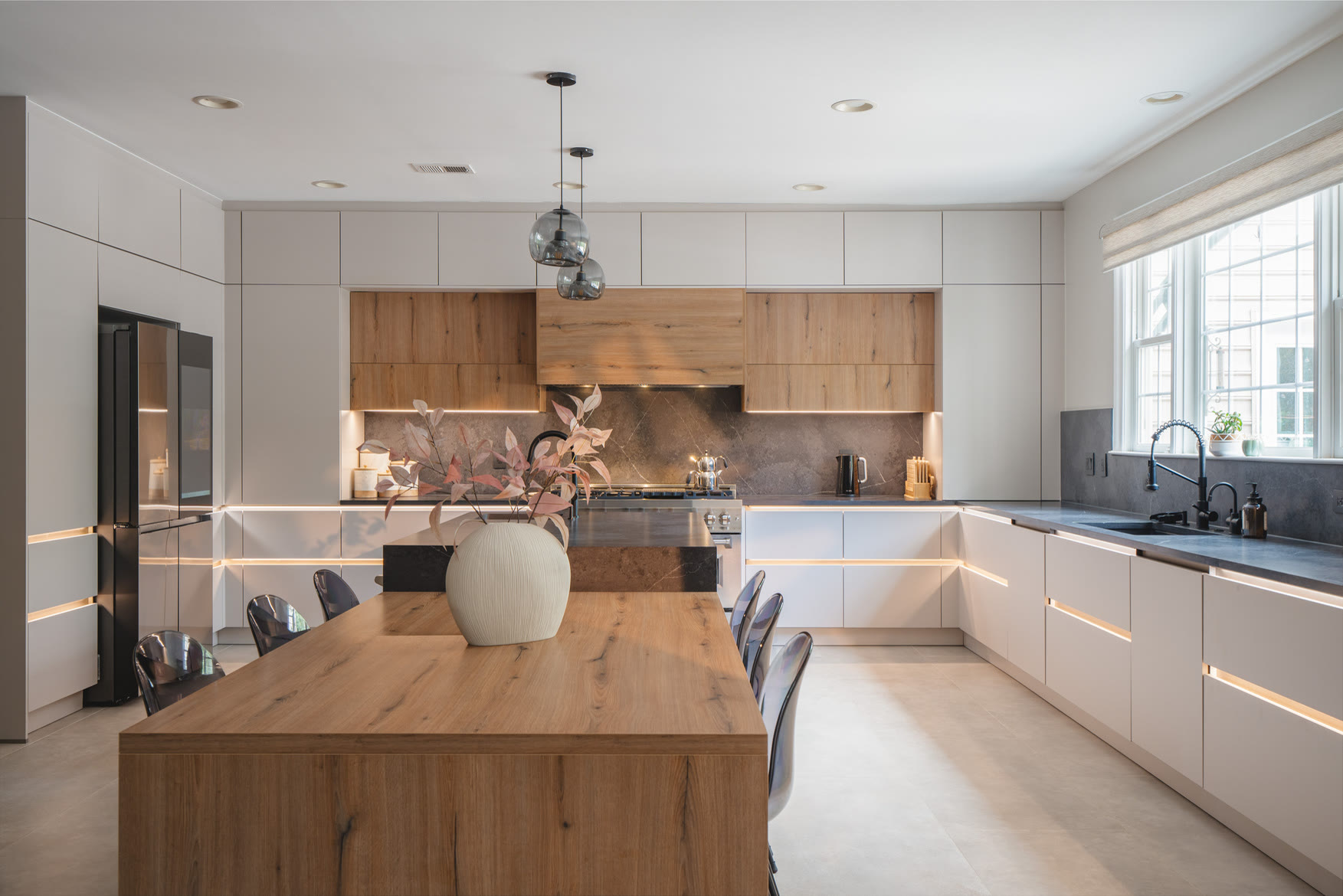 Finished kitchen with white cabinetry, a wood-grain island with seating, and warm pendant lights.