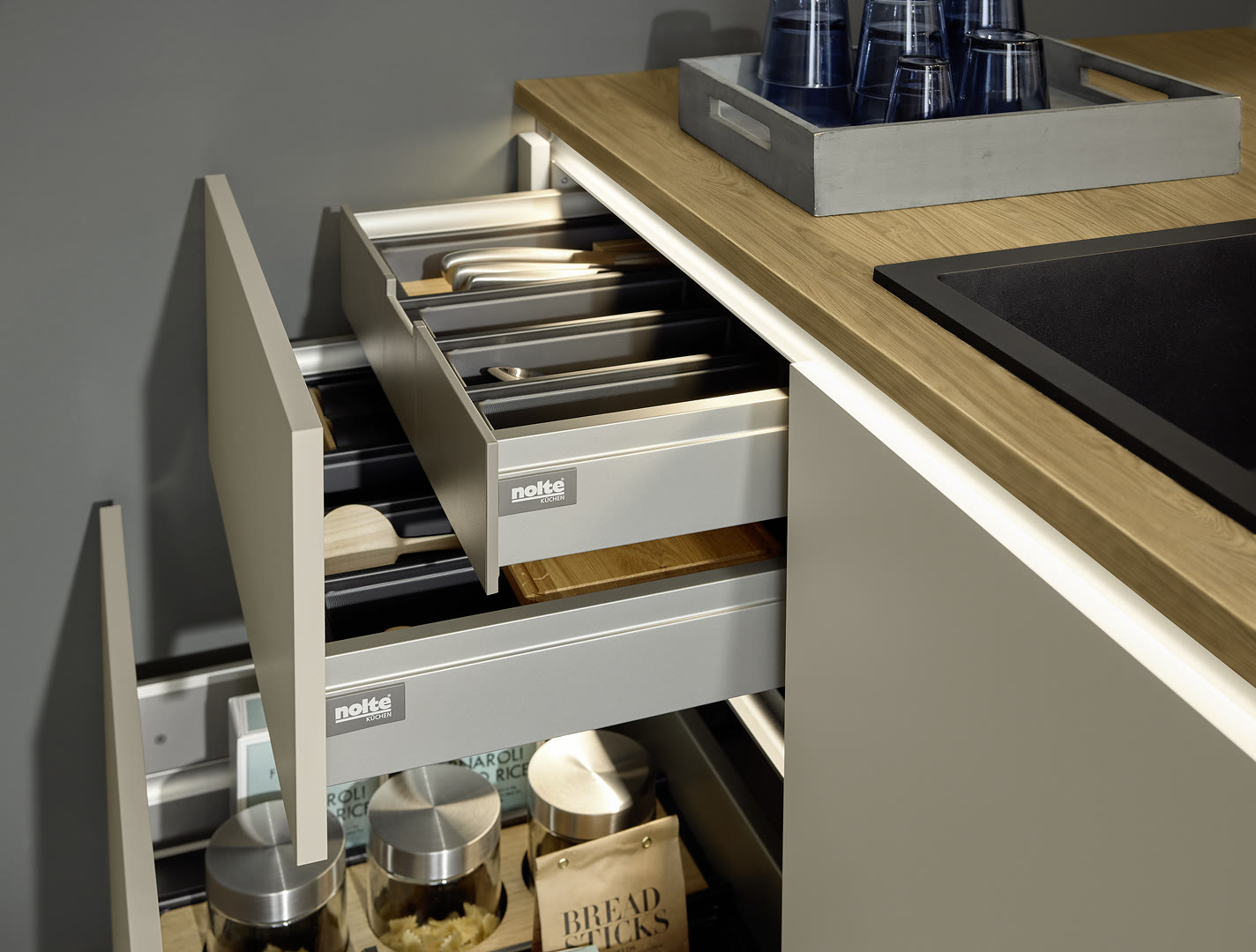 White handleless base cabinet with stacked drawers organizing utensils and cookware.