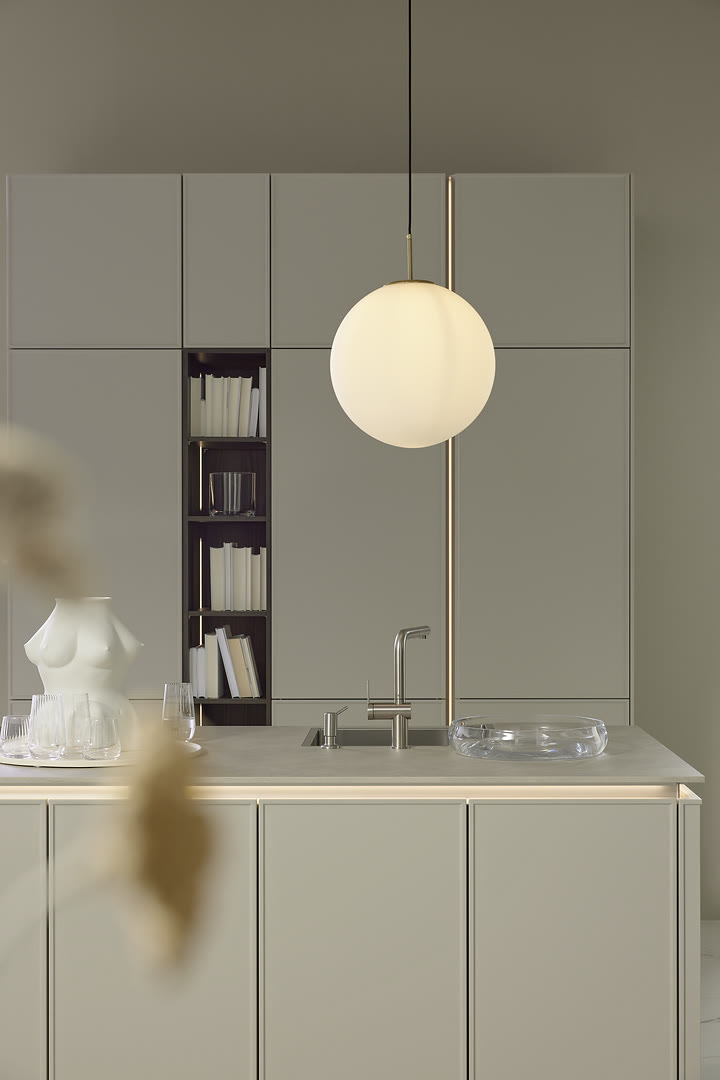 Compact kitchen with light grey handleless cabinets, a white counter with integrated sink, and open shelving.